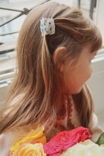 Load image into Gallery viewer, Child with floral hair clip and flower headband indoors
