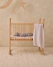 Load image into Gallery viewer, A light natural wood rocking crib with a baby sleeping inside, styled in a warm, neutral nursery with a beige wall decorated with a star and moon mural.
