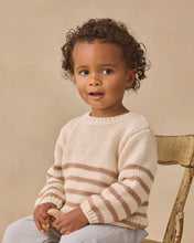 Load image into Gallery viewer, A toddler with curly brown hair sits on a rustic wooden chair, wearing a cream and brown striped knit sweater and light gray pants against a warm beige background.
