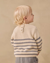 Load image into Gallery viewer, A toddler with blonde hair is shown from the back wearing a cream knit sweater with horizontal gray stripes and a buttoned neckline, set against a solid beige background.
