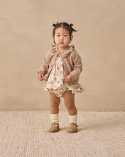 Load image into Gallery viewer, A toddler girl stands against a warm beige studio backdrop wearing a light brown knit cardigan over a cream dress with a small animal print, white socks, and tan shoes.
