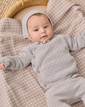 Load image into Gallery viewer, A baby lying on a beige and brown plaid blanket, wearing a light gray knit cardigan and matching bonnet with small wooden buttons.

