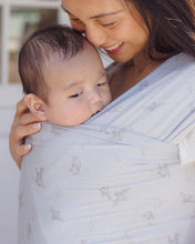 Load image into Gallery viewer, Woman holding a baby in a light blue wrap with a subtle pattern.

