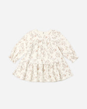 Load image into Gallery viewer, A long-sleeve baby girl's tiered dress with a delicate beige and brown floral pattern on an off-white background, shown flat on a light gray background.
