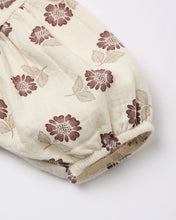 Load image into Gallery viewer, A close-up of a cream-colored fabric garment, likely a baby romper or skirt, featuring an all-over floral print in dusty mauve and beige, finished with a gathered elastic cuff.
