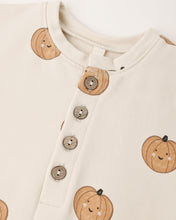 Load image into Gallery viewer, Close-up of a cream-colored baby top featuring a cute pumpkin print and a buttoned henley neckline.
