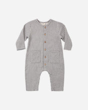 Load image into Gallery viewer, A baby long-sleeve romper in a small black and white gingham check pattern, featuring a snap-button front and two front patch pockets, shown on a plain light gray background.
