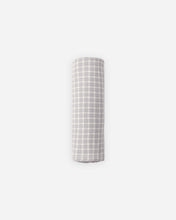 Load image into Gallery viewer, A rolled-up fabric item, likely a muslin swaddle or blanket, featuring a light gray and white gingham checkered pattern, centered on a solid light gray background.
