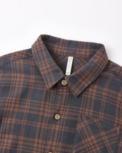 Load image into Gallery viewer, A close-up of a plaid button-down shirt collar and upper chest. The fabric has a dark slate gray base with a rust-brown and orange plaid pattern, featuring brown buttons and a white neck label.
