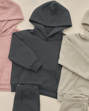Load image into Gallery viewer, A dark charcoal gray hooded sweatshirt and matching sweatpants laid flat on a light beige background, surrounded by cropped views of the same matching sets in dusty pink and light beige.
