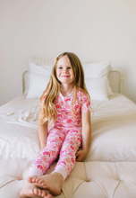 Load image into Gallery viewer, Young girl in pink pajamas sitting on a bed
