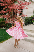 Load image into Gallery viewer, Young girl in a pink dress standing on a sidewalk with cherry blossom trees in the background.
