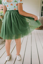 Load image into Gallery viewer, Person wearing a light blue top with rainbow designs and a green tulle skirt on a wooden deck.
