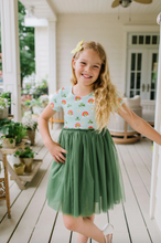 Load image into Gallery viewer, Young girl in a colorful top and green tutu skirt standing on a wooden porch.
