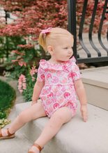 Load image into Gallery viewer, Child wearing a pink onesie sitting on steps outdoors.
