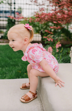 Load image into Gallery viewer, Baby in a pink outfit sitting on a stone ledge with greenery in the background

