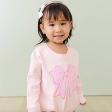Load image into Gallery viewer, Young girl wearing a pink sweater with a large bow design against a light green background
