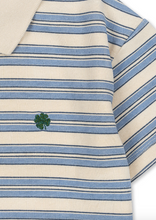 Load image into Gallery viewer, Close-up of a blue and white striped shirt with a green clover emblem.
