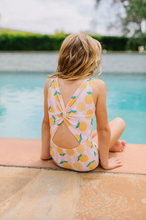 Load image into Gallery viewer, Child sitting by a pool wearing a colorful swimsuit with lemon pattern.
