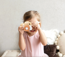 Load image into Gallery viewer, Child holding a toy camera up to their face in a cozy indoor setting
