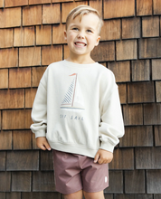 Load image into Gallery viewer, Child wearing a white sweatshirt with a sailboat design in front of a wooden wall.

