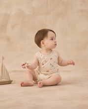 Load image into Gallery viewer, Baby sitting on a beige surface holding a toy boat, wearing a floral romper.
