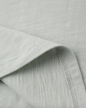 Load image into Gallery viewer, Close-up of light green fabric with a subtle texture and visible stitching.

