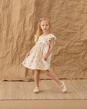 Load image into Gallery viewer, Young girl in a dress standing against a textured brown background
