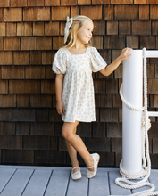 Load image into Gallery viewer, Young girl in a white dress standing next to a wooden wall
