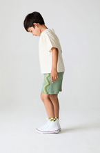 Load image into Gallery viewer, Child wearing a white t-shirt and green shorts on a plain background
