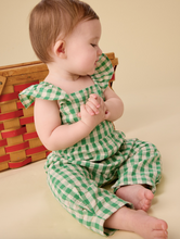 Load image into Gallery viewer, Baby wearing a green and white checkered outfit sitting on a beige surface with a wooden toy in the background.
