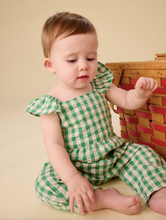 Load image into Gallery viewer, Baby wearing a green checkered outfit sitting on a beige floor with a wooden basket in the background.

