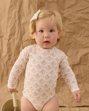 Load image into Gallery viewer, Child wearing a floral long-sleeve bodysuit against a textured brown background
