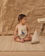 Load image into Gallery viewer, Baby sitting on a textured surface with a paper boat and wooden stool against a brown paper backdrop
