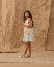 Load image into Gallery viewer, Young girl in a striped dress holding a woven bag against a textured brown background
