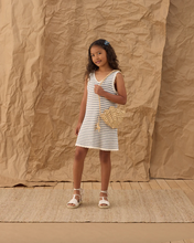 Load image into Gallery viewer, Young girl in a striped dress holding a woven bag against a textured brown backdrop

