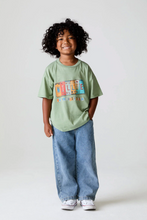 Load image into Gallery viewer, Child wearing a green t-shirt with colorful text design and blue jeans on a white background
