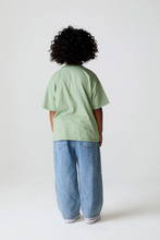 Load image into Gallery viewer, Person wearing a light green t-shirt and blue jeans standing against a white background
