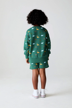 Load image into Gallery viewer, Child wearing a green outfit with animal patterns on a white background
