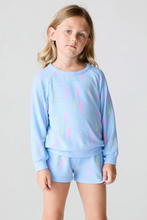 Load image into Gallery viewer, Young girl wearing a light blue outfit with colorful abstract patterns on a plain background
