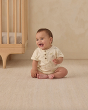 Load image into Gallery viewer, Baby sitting on a beige floor next to a wooden crib
