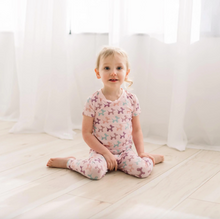 Load image into Gallery viewer, Child sitting on a light-colored floor wearing a pink pajama set with dog pattern.
