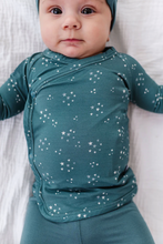 Load image into Gallery viewer, Baby wearing a teal outfit with star patterns on a white background
