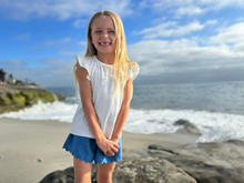 Load image into Gallery viewer, Young girl standing on a beach with ocean waves and sky in the background
