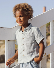 Load image into Gallery viewer, Child wearing a light blue shirt standing on a white wooden railing with a clear sky background
