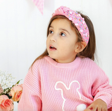 Load image into Gallery viewer, Young girl wearing a pink sweater and headband with flowers in the background
