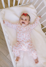 Load image into Gallery viewer, Baby in a crib wearing a pink onesie with a pattern
