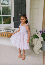 Load image into Gallery viewer, Young girl in a pink dress standing on a porch with decorative elements.

