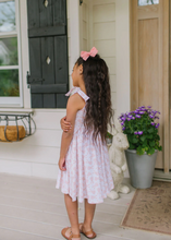 Load image into Gallery viewer, Child in a pink dress standing on a porch with a rabbit statue and potted plant.

