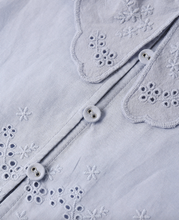 Load image into Gallery viewer, Close-up of a light purple fabric with embroidered snowflake patterns and buttons.
